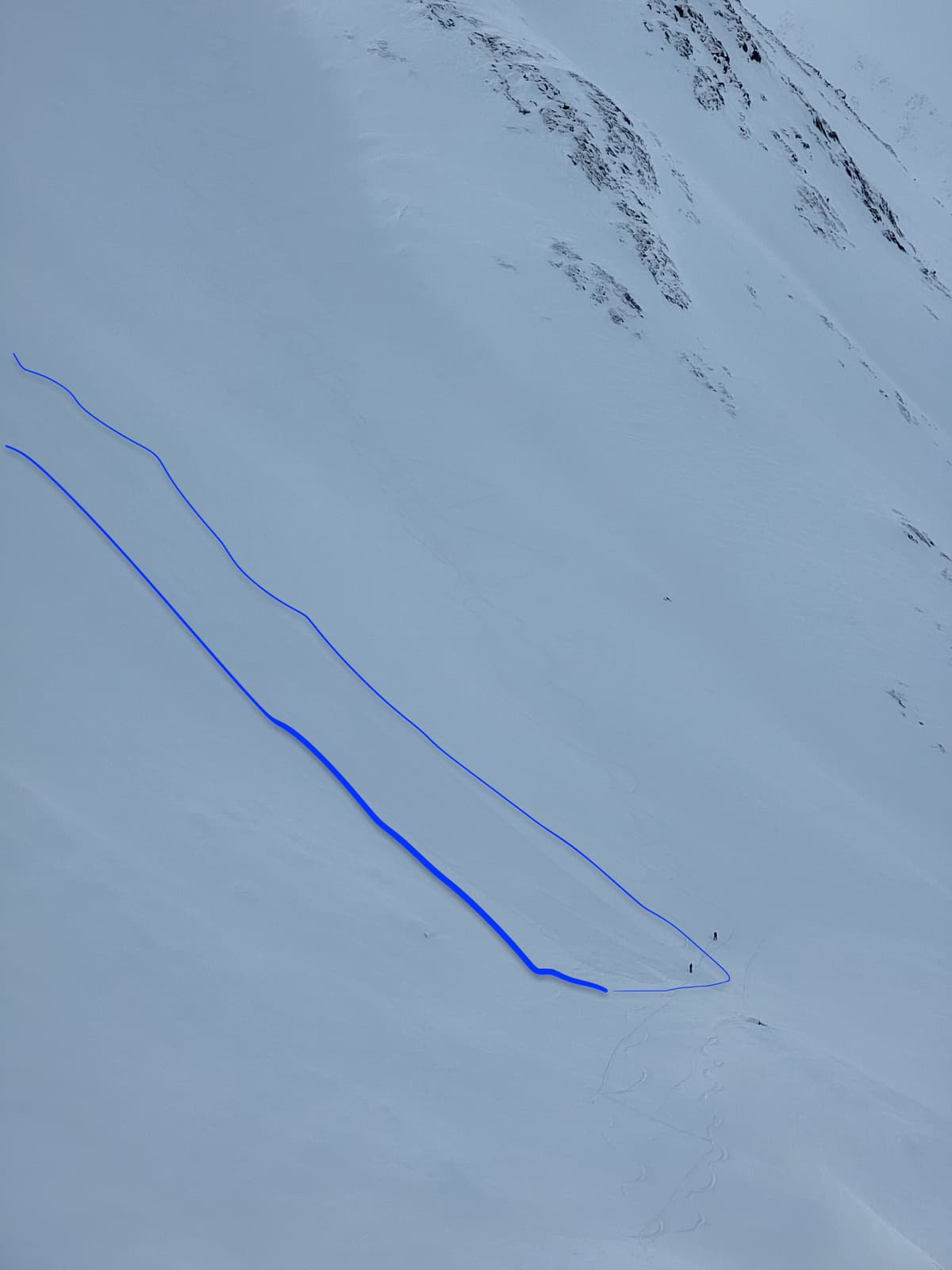 Sluff/loose dry debris, outlined in blue. Two skiers are at the base (for scale).