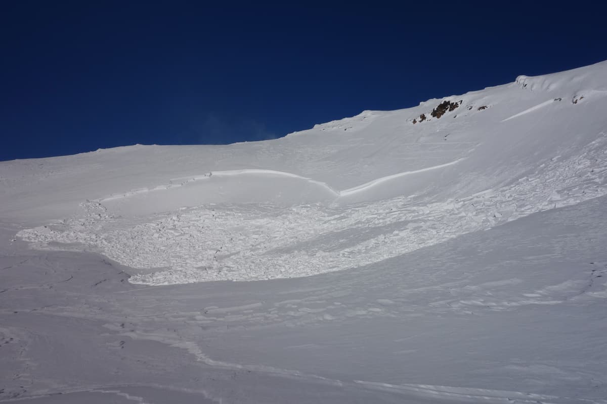 Skier tracks visible top right below rocks.